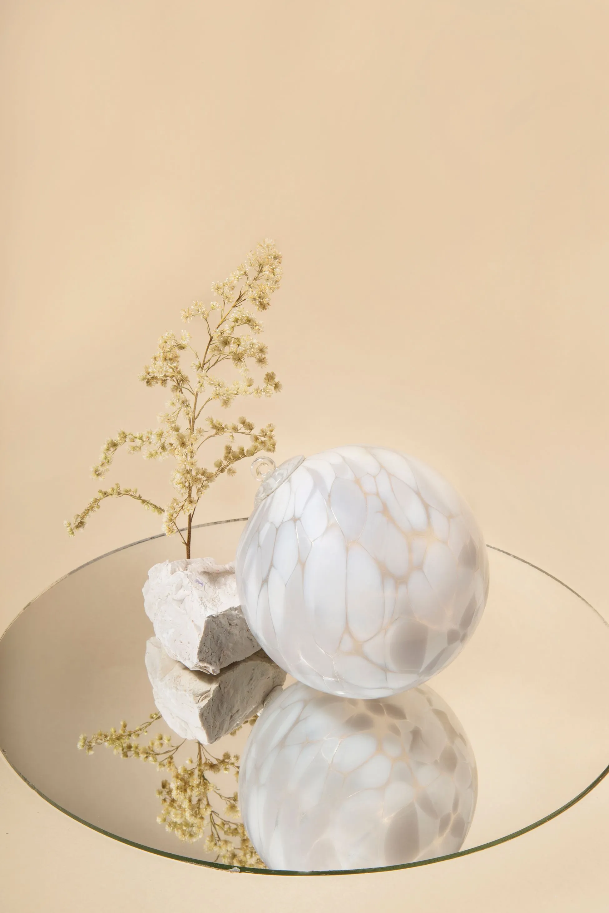Glass ornament resting on a mirror with rock and plant